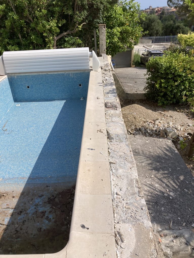 Exposed pool edge and coping stones removed during inspection.